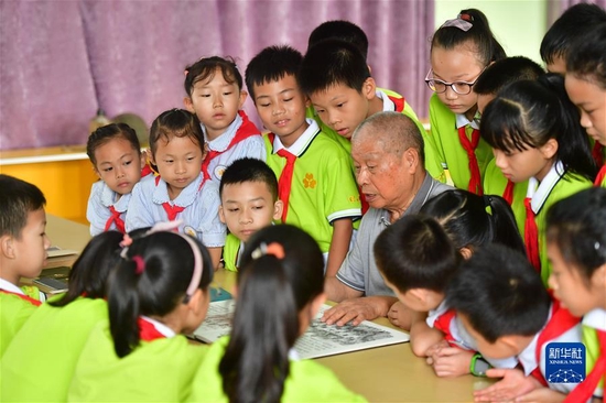 在广西柳州市柳北区桂景湾路小学，老党员给小学生讲述党史故事（6月9日摄）。新华社记者 黄孝邦 摄