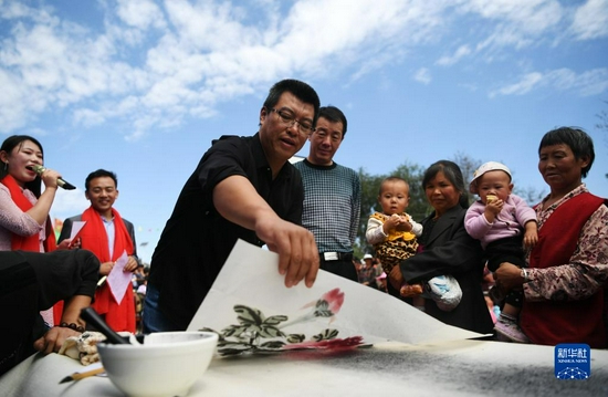 2018年9月8日，在“快乐一座村庄”送欢乐下基层公益活动中，文艺志愿者郭永东（左三）在甘肃省静宁县甘沟镇梁岔村为村民现场作画。新华社记者 陈斌 摄